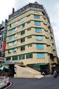 台南的住宿－哥爸妻夫商務飯店-林森館 ，一座高大的建筑,前面停有一辆摩托车