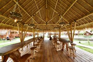 a large pavilion with tables and chairs on a deck at Beranda Ecolodge in Gili Air