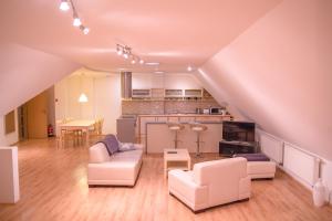 a living room with white furniture and a kitchen at Old Town Apartment in Trenčín