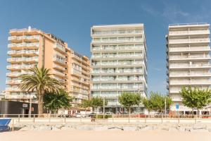2 grands bâtiments à côté d'une plage bordée de palmiers dans l'établissement Pierre & Vacances Blanes Playa, à Blanes
