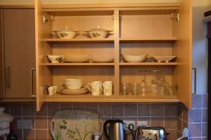 a kitchen cabinet filled with bowls and dishes on shelves at Teign Head Apartment in Newton Abbot