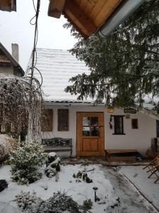 una casa cubierta de nieve con una puerta de madera en Kis Sziget Vendégház en Nagybörzsöny