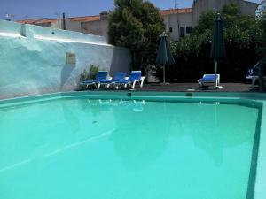 a swimming pool with blue chairs and umbrellas at Hotel de Moura in Moura