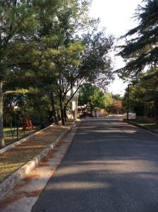 una calle vacía con árboles a los lados de la carretera en Robinson Apartamentos SOLO FAMILIAS en Villa Carlos Paz