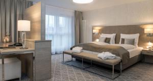 ein Hotelzimmer mit einem großen Bett und einem Schreibtisch in der Unterkunft Victor's Residenz-Hotel Teistungenburg in Teistungen