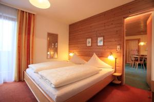 ein Schlafzimmer mit einem großen Bett und einer Holzwand in der Unterkunft Wellness Pension Hollaus in Kirchberg in Tirol