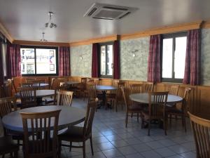 a dining room with tables and chairs and windows at Hotel Le Centre in Brides-les-Bains