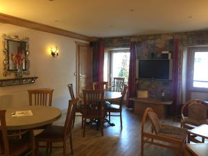 a dining room with tables and chairs and a television at Hotel Le Centre in Brides-les-Bains