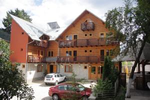a large wooden house with cars parked in a parking lot at La Cristina in Sinaia