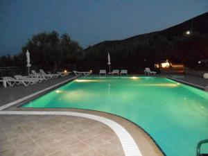 ein großer Pool mit Stühlen und Tischen in der Nacht in der Unterkunft Anatoli Labreon in Agia Marina