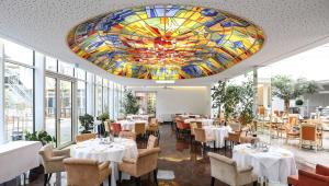 una sala da pranzo con tavoli e soffitto in vetro colorato di Hotel La Strada a Kassel