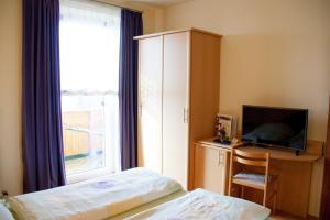 ヴォルフスベルクにあるGasthof Pension Zollerのベッドルーム(ベッド1台、テレビ、窓付)