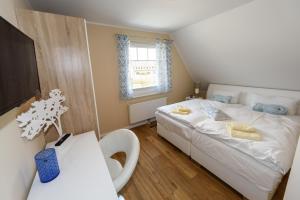 a bedroom with a white bed and a window at Premiumhaus Bodden und Mehr-Brise in Born