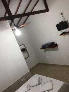 a room with a bed and a television on the wall at Pousada Recanto das pedras in São Gonçalo do Rio das Pedras