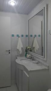 Baño blanco con lavabo y espejo en Seu cantinho em Geribá, en Búzios