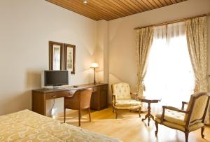 a bedroom with a desk with a television and a bed at Bodegas Hacienda Albae in Argamasilla de Alba