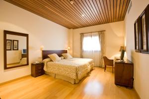 a bedroom with a bed and a desk and a mirror at Bodegas Hacienda Albae in Argamasilla de Alba
