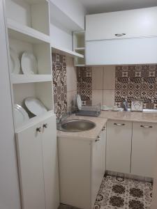a kitchen with white cabinets and a sink at cozy apartment in a quiet area in Craiova