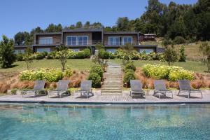 a house with chairs and a swimming pool at Lake Lodge in Pucón