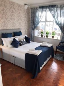 a bedroom with a large bed with blue and white pillows at Finchley Apartment in London