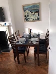 a dining room table with four chairs and a painting at Finchley Apartment in London