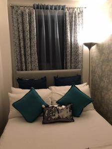 a bed with green and white pillows and a lamp at Finchley Apartment in London