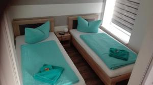 2 Betten in einem kleinen Zimmer mit blauen Kissen in der Unterkunft Ferienwohnungen Paul und Dorothea in Döllstädt