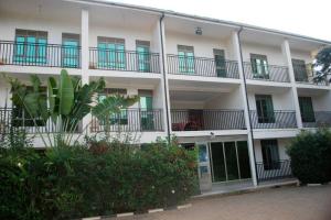 a large white building with balconies and plants at Palm world Hotels Mbarara in Mbarara