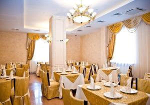 einen Bankettsaal mit Tischen, Stühlen und einem Kronleuchter in der Unterkunft Hotel Elbuzd in Rostow am Don