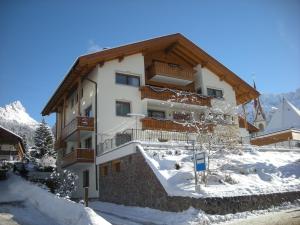 un edificio con nieve delante en Garni Hotel Rezia en Selva di Val Gardena