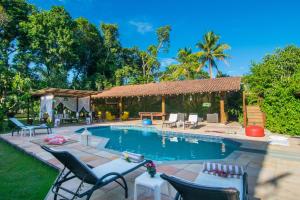 a swimming pool with chairs and a house at Trancoso Pousada in Trancoso