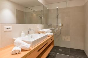 a bathroom with a white sink and a shower at Tonzhaus Hotel in Senales