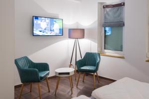 オスターホルツ・シャルムベックにあるHotel Zur Alten Börseの椅子2脚、ランプ、テレビが備わる客室です。