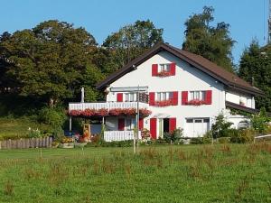 ein weißes Haus mit roten Rollläden und einem Hof in der Unterkunft appartement "bellevue" in Les Breuleux
