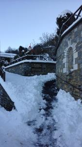 a stone wall with snow next to a river at Malevos Traditional Houses in Áyios Pétros