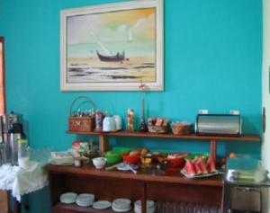 a room with a blue wall with a shelf of food at Hotel Recanto do Sol in Cananéia