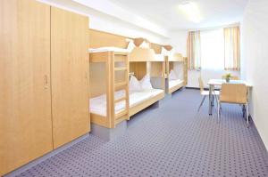 a room with bunk beds and a table and a desk at Jugendgästehaus Linz in Linz