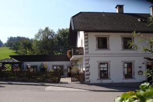 een wit huis met een zwart dak en een hek bij Gästehaus Daurer in Reinsberg