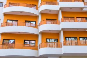 une façade d'un immeuble d'appartements avec des balcons orange dans l'établissement Le Feto 3, à Dakar
