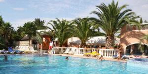 a pool at a resort with people in the water at Camping La Croix du Sud in Le Barcarès