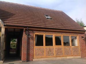 a red brick garage with a large wooden door at Woodview Lodge in Chesterfield