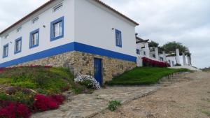 a white and blue building with flowers in front of it at Amieira Agroturismo in Odemira