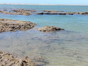 a body of water with rocks and the ocean at Pousada Brisa Do Pontal in Fortim