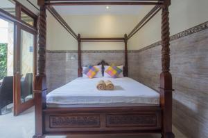 a bedroom with a four poster bed with two wooden logs at Jepun Bali Ubud Homestay in Ubud