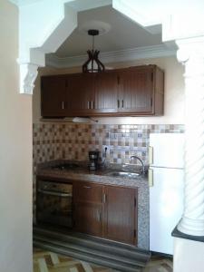 a kitchen with wooden cabinets and a sink and a refrigerator at Location Vacances Casablanca Tamaris in Casablanca