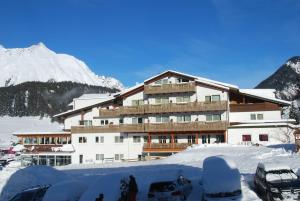 een met sneeuw bedekt gebouw met auto's die voor het gebouw geparkeerd staan bij Alpenhotel Regina in Nauders