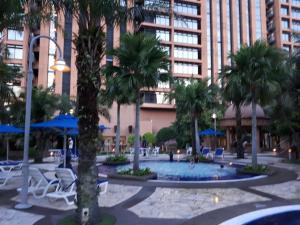 a courtyard with chairs and palm trees in front of a building at Robinsons Apartments at Times Square KL in Kuala Lumpur