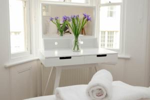 uma casa de banho branca com um vaso de flores sobre uma mesa em Central Regency Town House em Brighton & Hove