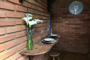 a table with a vase of flowers on a brick wall at sítio cambará in Aiuruoca