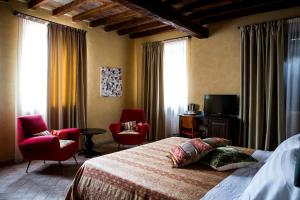 ein Schlafzimmer mit einem Bett, 2 Stühlen und einem TV in der Unterkunft Relais Cascina Scottina in Cadeo